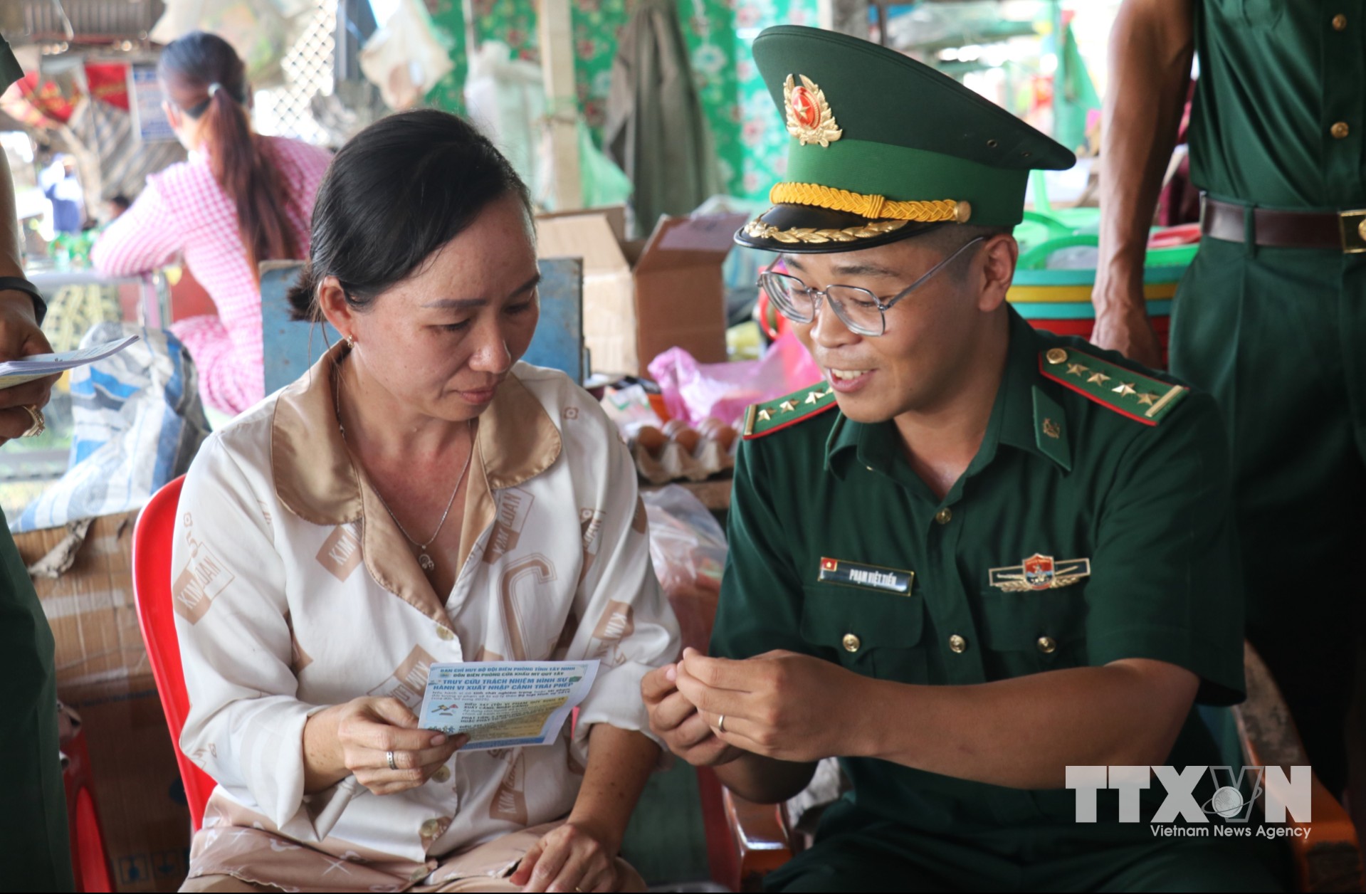 Giữa khu chợ biên giới, Đại úy Phạm Việt Tiến kiên nhẫn giải thích cho người dân những vấn đề liên quan đến an ninh, trật tự, bằng cách nói chuyện gần gũi, dễ hiểu. (Ảnh: Bùi Giang/TTXVN)